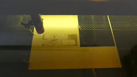 CO2 laser engraving machine processing a detailed custom photo portrait on a wood sheet with a red guide laser.