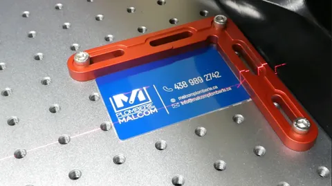 Fiber laser engraving machine stripping paint with micro-precision from a blue metal business card.