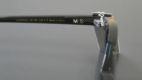Custom laser engraved "M S" initials monogrammed onto the inner arm of black plastic sunglasses.